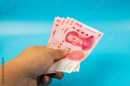Man hand holding China Note RMB100 Yuan Note on blue background