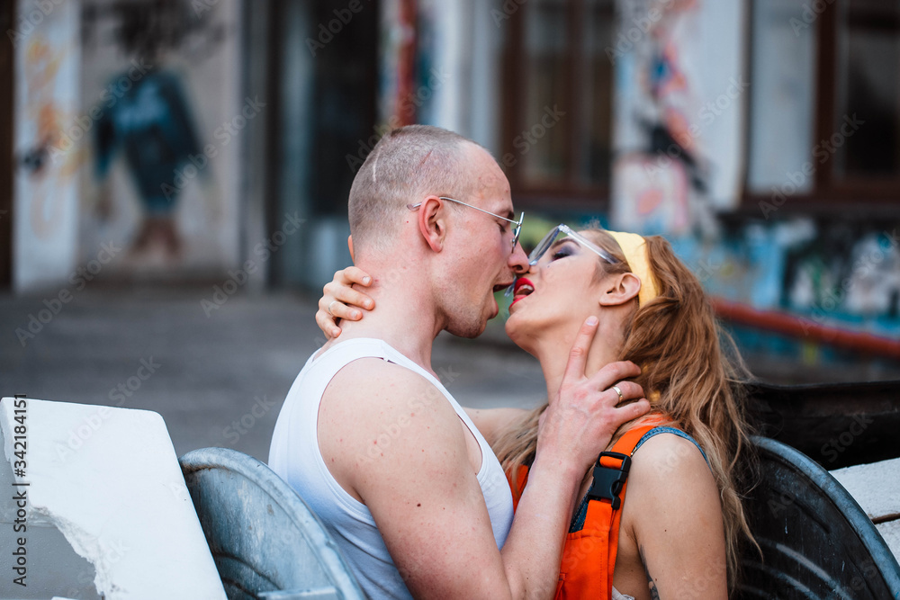 Young couple kissing between two garbage cans. Man and woman kissing. Love and passion.