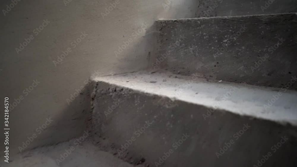 Close up on the steps in dark hall concrete gray walking up the stairs camera climbing no people in unknown dirty spooky dramatic building low angle 