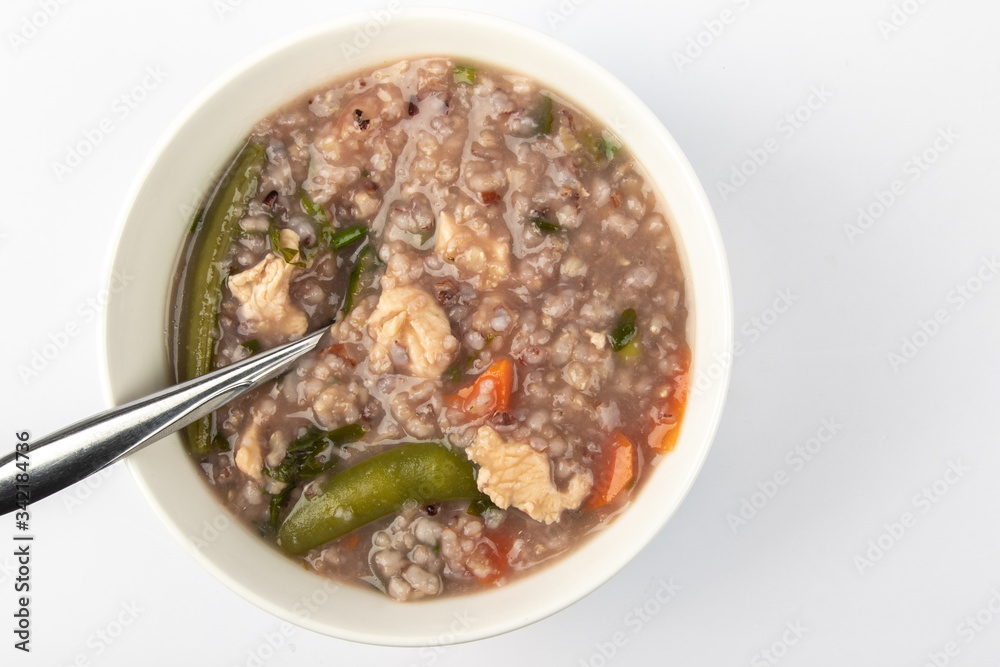 Delicious homemade brown rice porridge with few slice chicken, carrot and vegetable isolated on white background.  