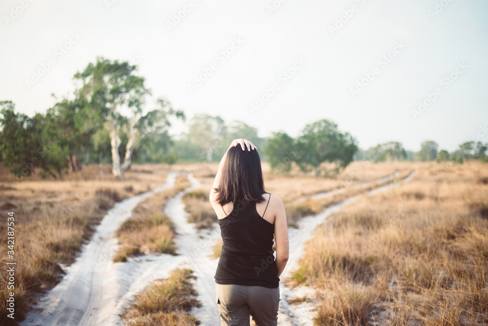 Beautiful solo woman traveller dtanding at savanna on during sunset,Relax and free time,Travel and vacation concept,Back view