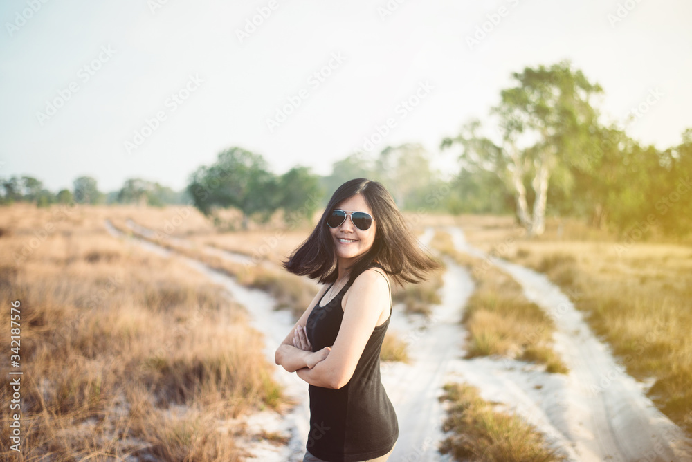 Beautiful solo woman traveller happy and smiling at savanna on during sunset,Relax and free time,Travel and vacation concept
