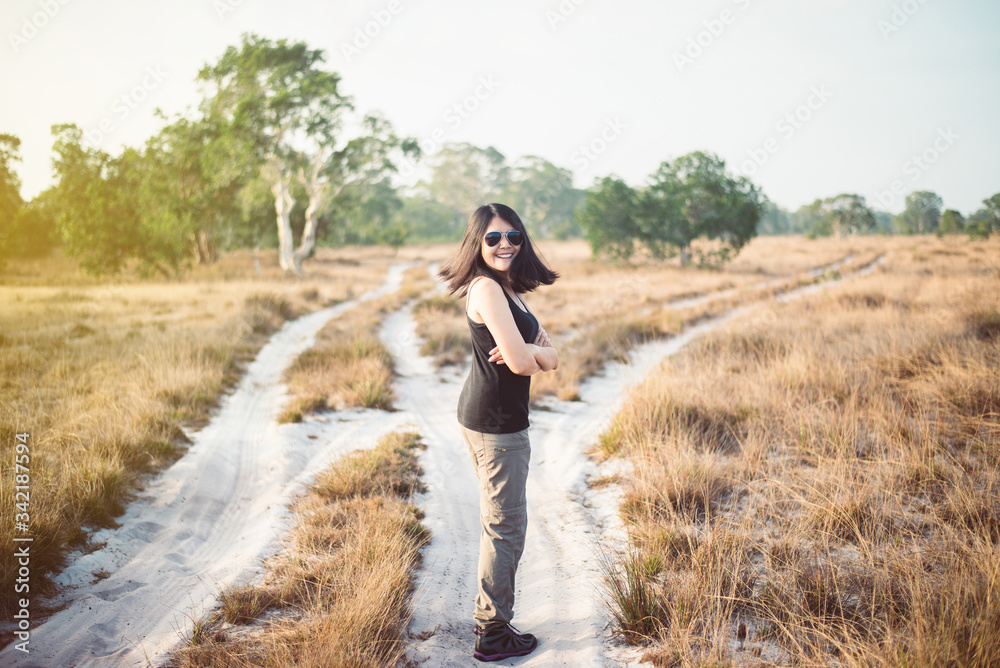 Beautiful solo woman traveller happy and smiling at savanna on during sunset,Relax and free time,Travel and vacation concept