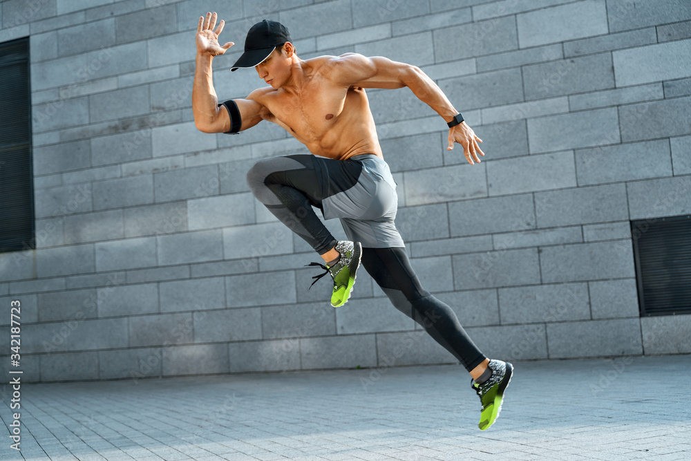 Foto Stock Sporty man running. Side view of active man training in the  city. Dynamic movement. Sports and healthy lifestyle | Adobe Stock