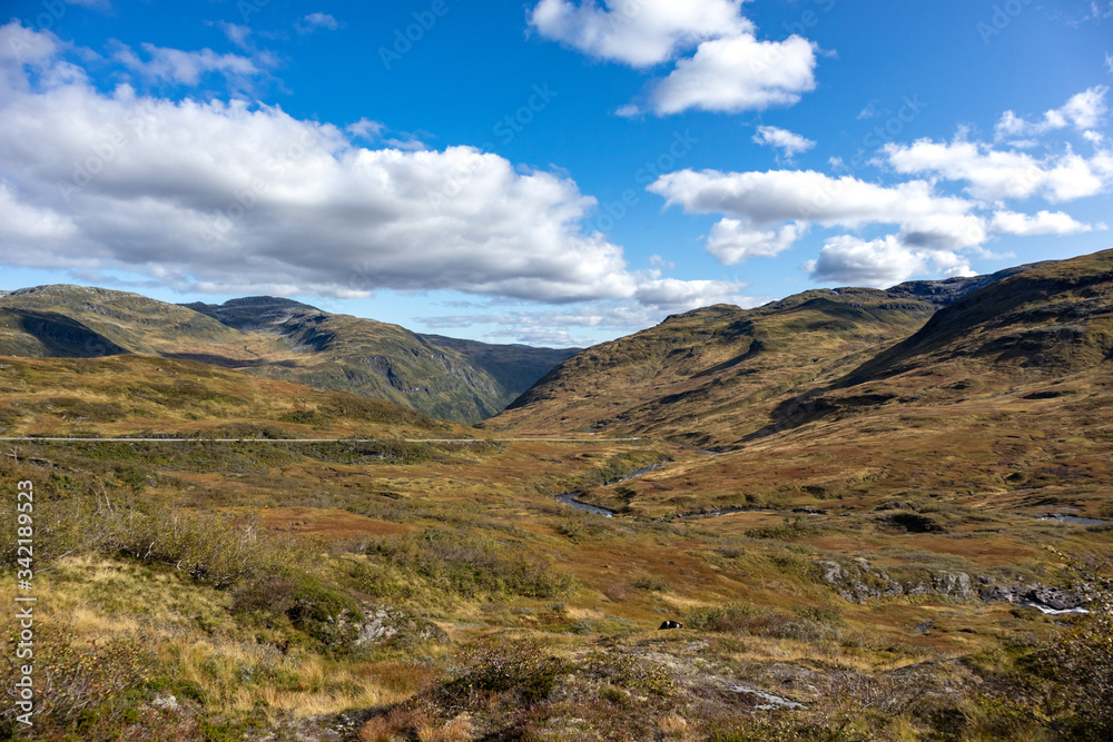 Norway sunny autumn panoramic view on mountains plateau with vibrant blue sky with clouds, epic trip to scandinavia