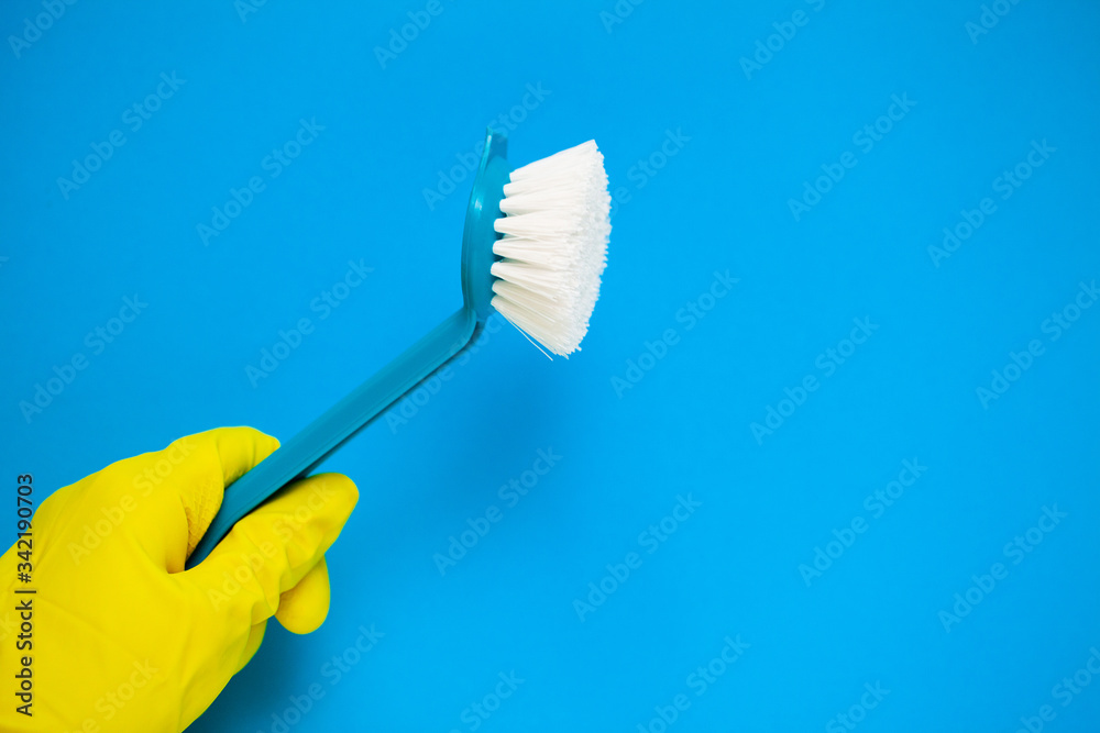 Closeup of hand in yellow mittens holding cleaning supplies. Closeup of hand in yellow mittens holding cleaning supplies.