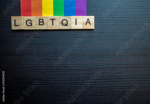 LGBTQIA word tiles on a rainbow flag on a black background 