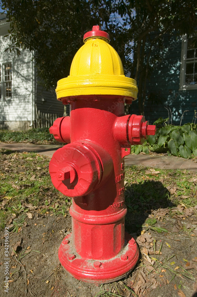 A red fire hydrant with a yellow top is seen roadside in New England A red fire hydrant with a yellow top is seen roadside in New England