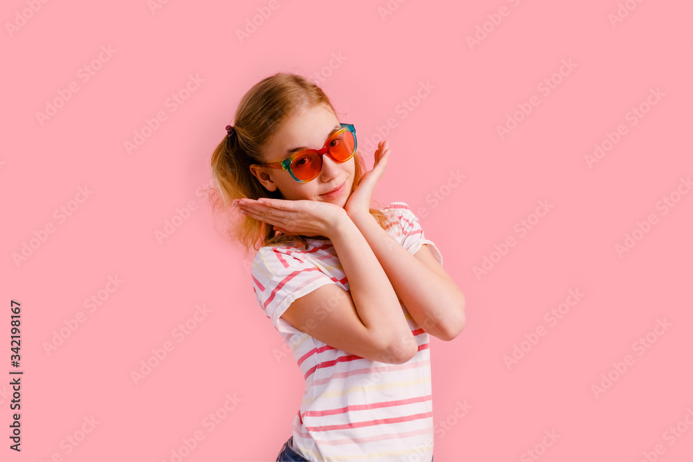 Emotional blonde teen girl in sparkle sunglasses laughing to camera on pink background Emotional blonde teen girl in sparkle sunglasses laughing to camera on pink background