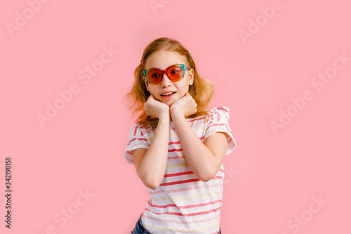 Emotional blonde teen girl in sparkle sunglasses laughing to camera on pink background