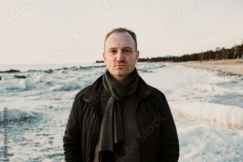 portrait of red haired handsome man on lake Baikal in winter in the sunset