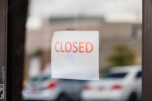 Closed sign on glass door to entrance of a business.