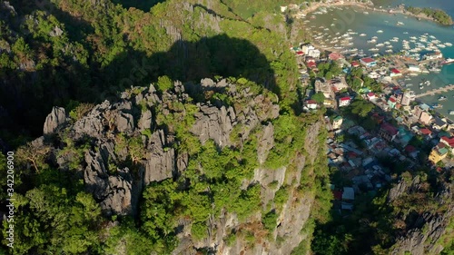 Aerial view rotation around beautiful limestone rocks of Taraw cliff with central El Nido town below in Palawan, Philippines photo