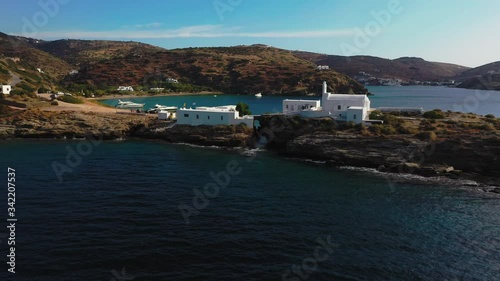 Aerial shot of the church of Chrisopigi on the cycladic island of Sifnos, Greece. Camera flies past the church and towards the small beach nearby. photo