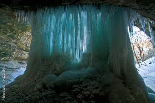 View from behind the frozen curtain of icicles of a frozen waterfall. photo