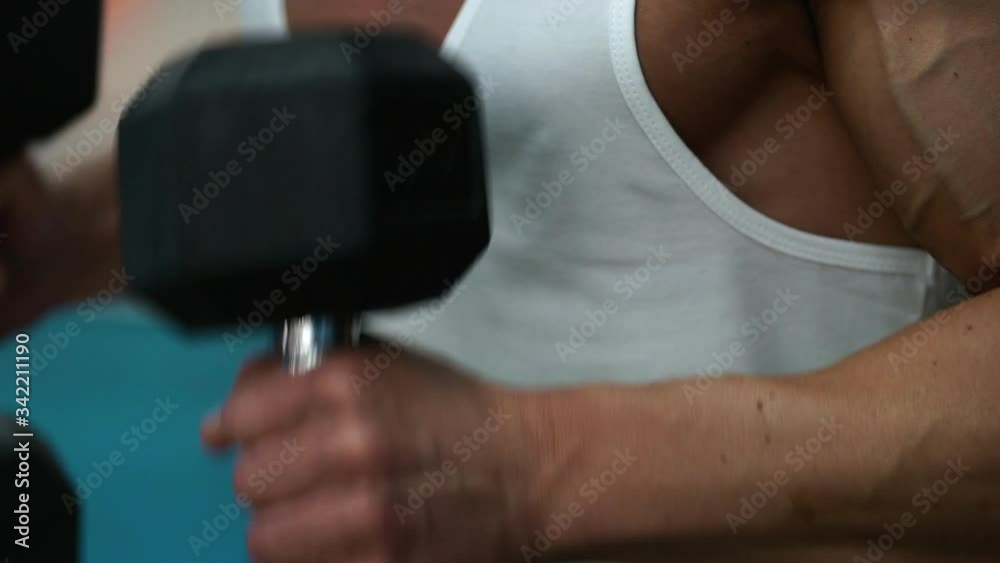 Close up shot of a bodybuilder doing hammer biceps at gym. Slow motion