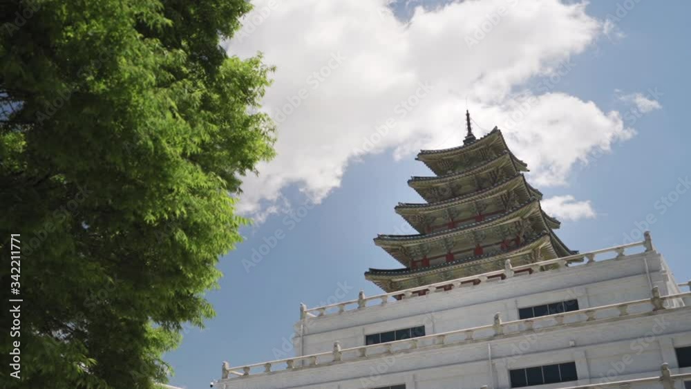 Low angle view of a Gyeongbokgung Palace structure in Seoul Korea beyond a tree on a clear day, wide shot dolly in slow motion. Low angle view of a Gyeongbokgung Palace structure in Seoul Korea beyond a tree on a clear day, wide shot dolly in slow motion.