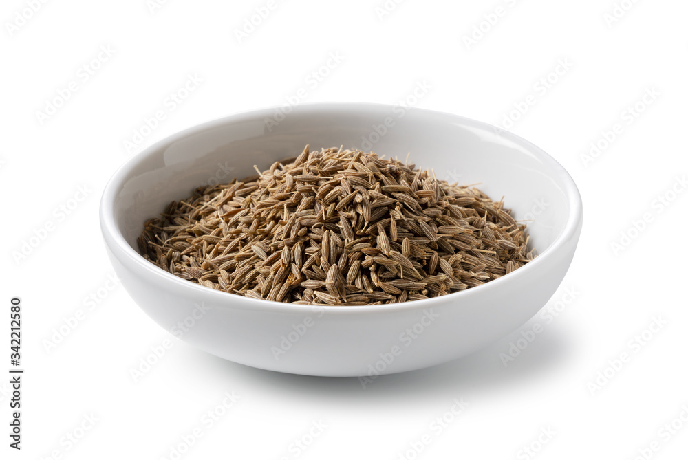 Cumin seeds in a plate placed on a white background Cumin seeds in a plate placed on a white background