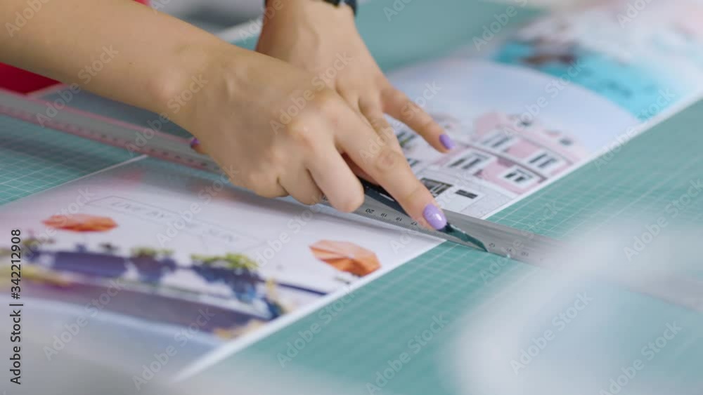 female hands cutting paper picturec useing sharp paper knife and marker at the table