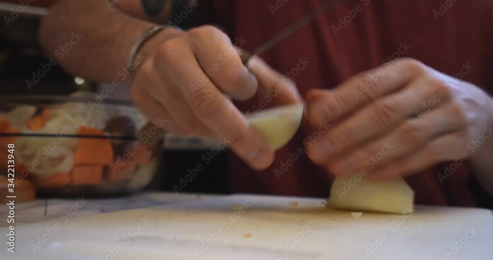 Close up, a sitting tattooed man, cut an onion n half with a big knife Close up, a sitting tattooed man, cut an onion n half with a big knife