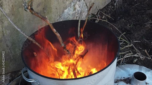 Slow motion shot looking into a metal drum with garden waste burning. photo