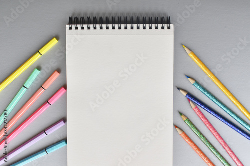 Libreta y colores sobre fondo color gris