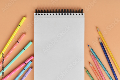 Libreta y colores sobre fondo color melón