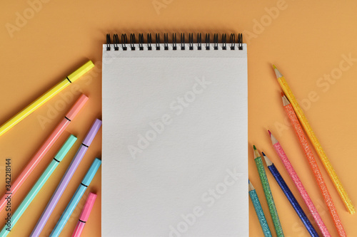 Libreta y colores sobre fondo color durazno