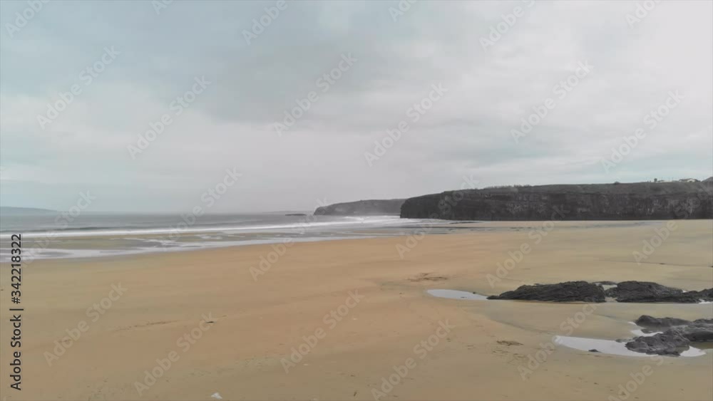 Trucking aerial shot of Ballybunion - irish beach - of the Wild Atlantic Way on an overcast day in Kerry county, Ireland. Trucking aerial shot of Ballybunion - irish beach - of the Wild Atlantic Way on an overcast day in Kerry county, Ireland.
