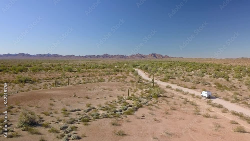 Aerial, drone shot following a camper van, driving on a dirt road, on a open desert, sunny day, in California, USA Aerial, drone shot following a camper van, driving on a dirt road, on a open desert, sunny day, in California, USA