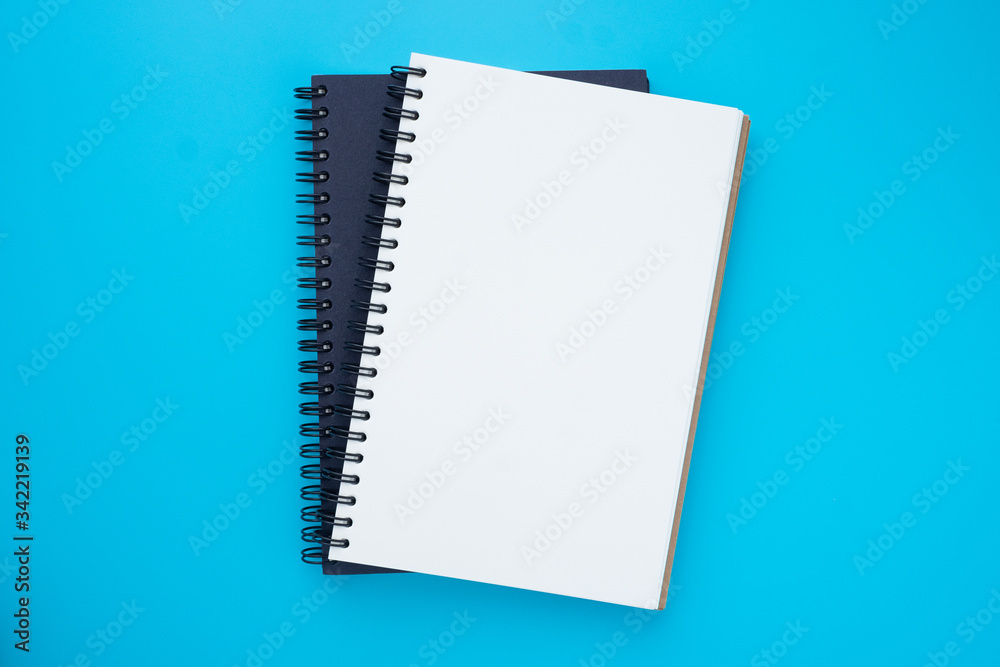Top view above of two spiral notebooks that open and close, stacked isolated on light blue background for design a mockup. Education and business concept. flat lay Top view above of two spiral notebooks that open and close, stacked isolated on light blue background for design a mockup. Education and business concept. flat lay