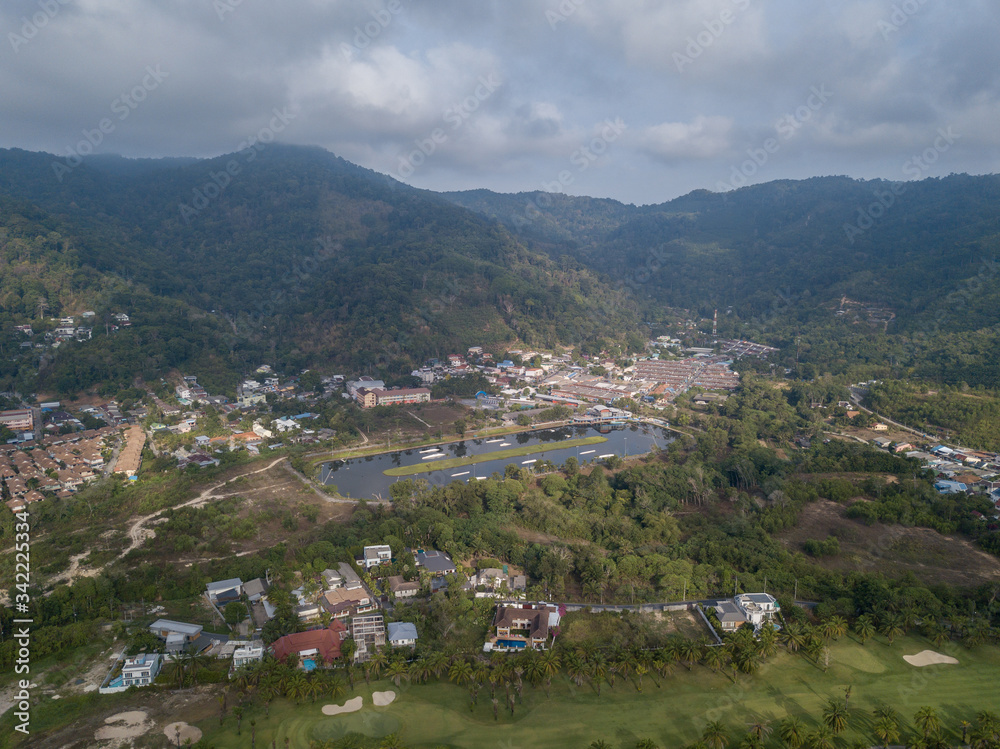 Fototapeta premium Beautiful lake located on a golf course surrounded by houses and mountains at dawn, photo from a drone. In the lake the reflection of the sky. Great background for travel and golf advertising.