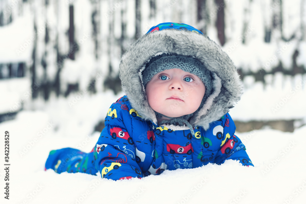 Caucasian infant is lying in his first snow.