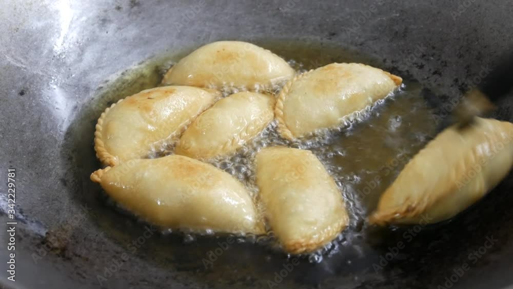 Curry puffs of local called Karipap fried using hot cooking oil inside a pan. It is one of the traditional cakes in Malaysia. Skin made from wheat flour mixture and the inside is potato and curry. Curry puffs of local called Karipap fried using hot cooking oil inside a pan. It is one of the traditional cakes in Malaysia. Skin made from wheat flour mixture and the inside is potato and curry.