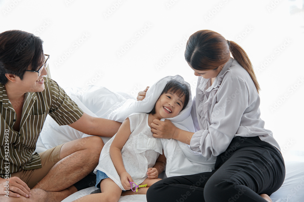 Happy young asian parents playing with adorable small daughters. they are having fun together in bedroom. Happy young asian parents playing with adorable small daughters. they are having fun together in bedroom.