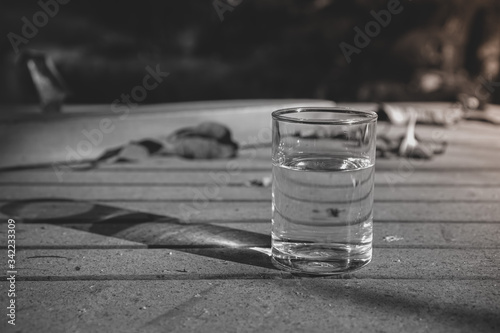 Black and white photography of glass of water on the dirty table.