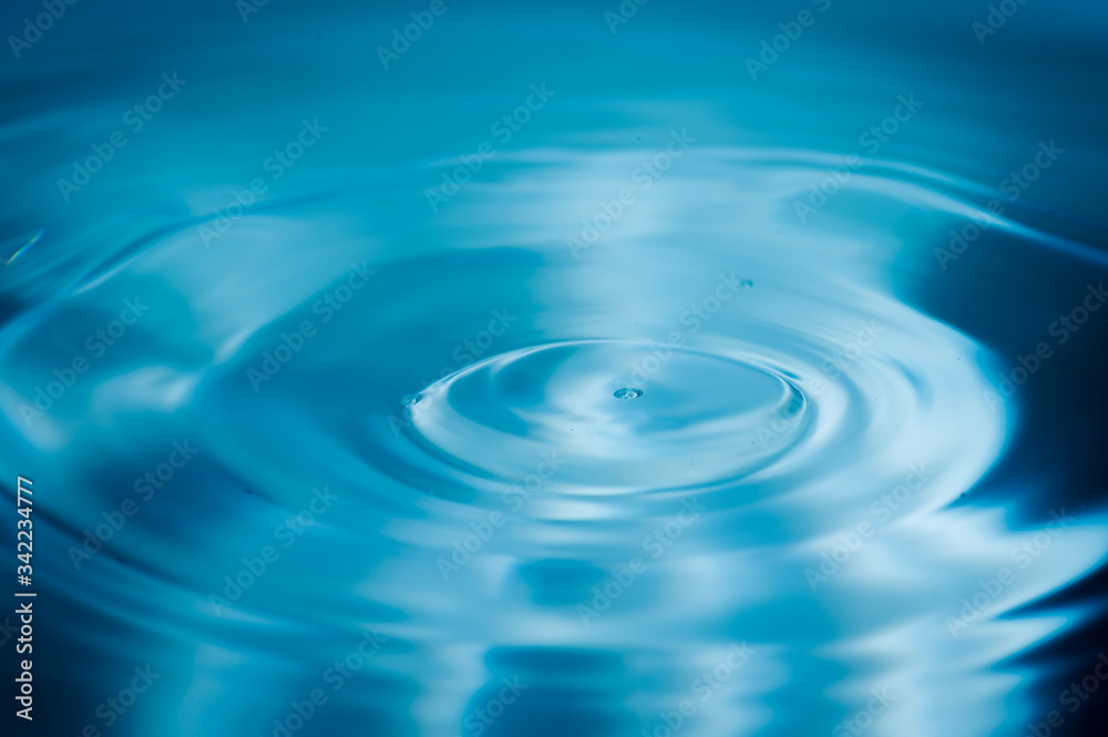 Water drops splash and circle reflextion background.Close up fresh water drops falling into the water and ripples of light blue.