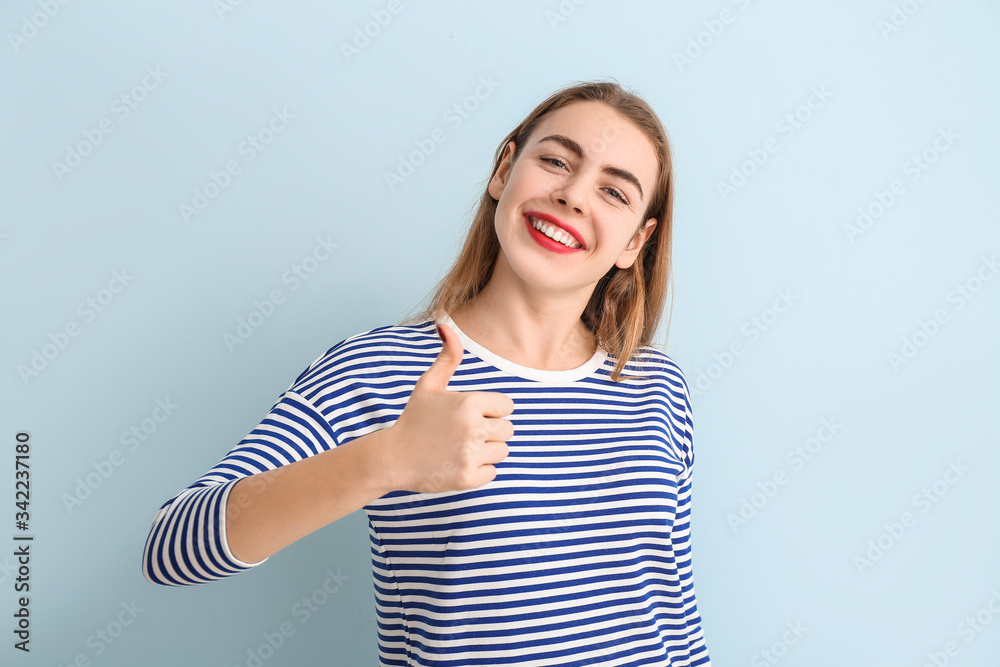Beautiful young woman showing thumb-up on color background Beautiful young woman showing thumb-up on color background