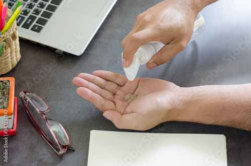 Close up on the hands of business people who have to work at home protect against viruses, Covid-19 cleans hands with sanitizing gel on bankground the desk working.