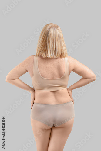 Overweight woman on grey ba...