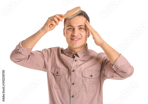 Handsome young man brushing hair on white background