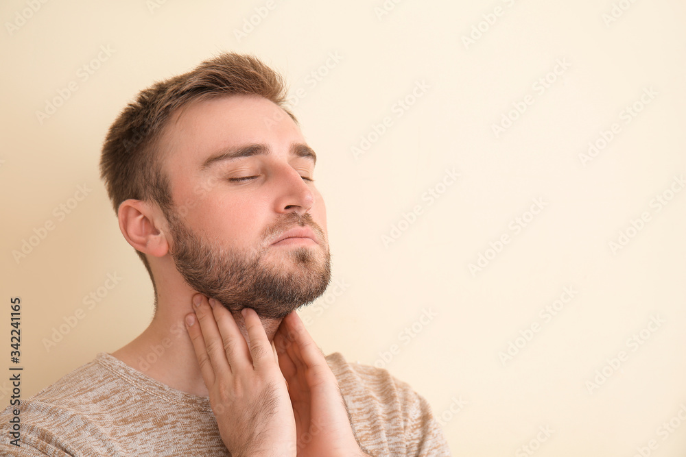 Obraz premium Young man checking thyroid gland on color background
