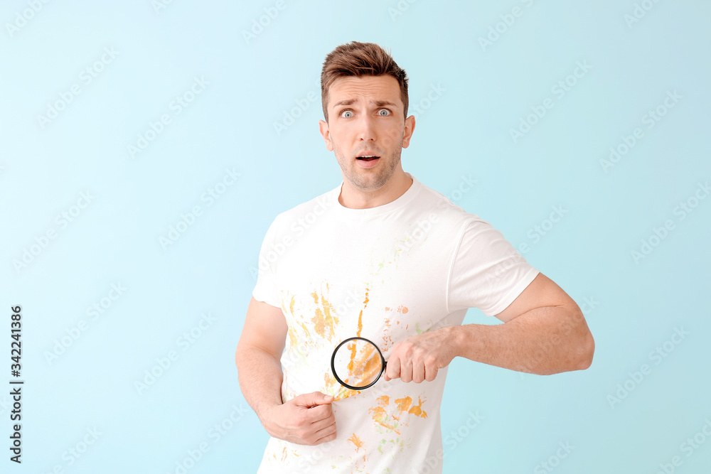 Troubled man in dirty clothes and with magnifying glass on color background Troubled man in dirty clothes and with magnifying glass on color background