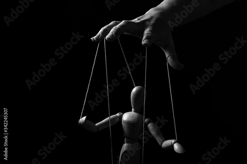 Photo Conceptual image of a hand with strings to control a marionette in monochrome