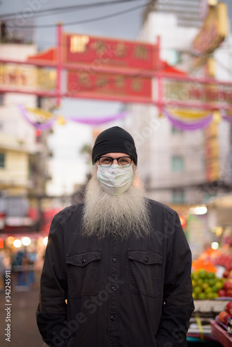 Mature bearded tourist man wearing mask for protection from corona virus outbreak in Chinatown