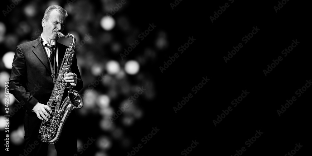 Obraz premium Saxophone player isolated at the left border of a black background (black and white)
