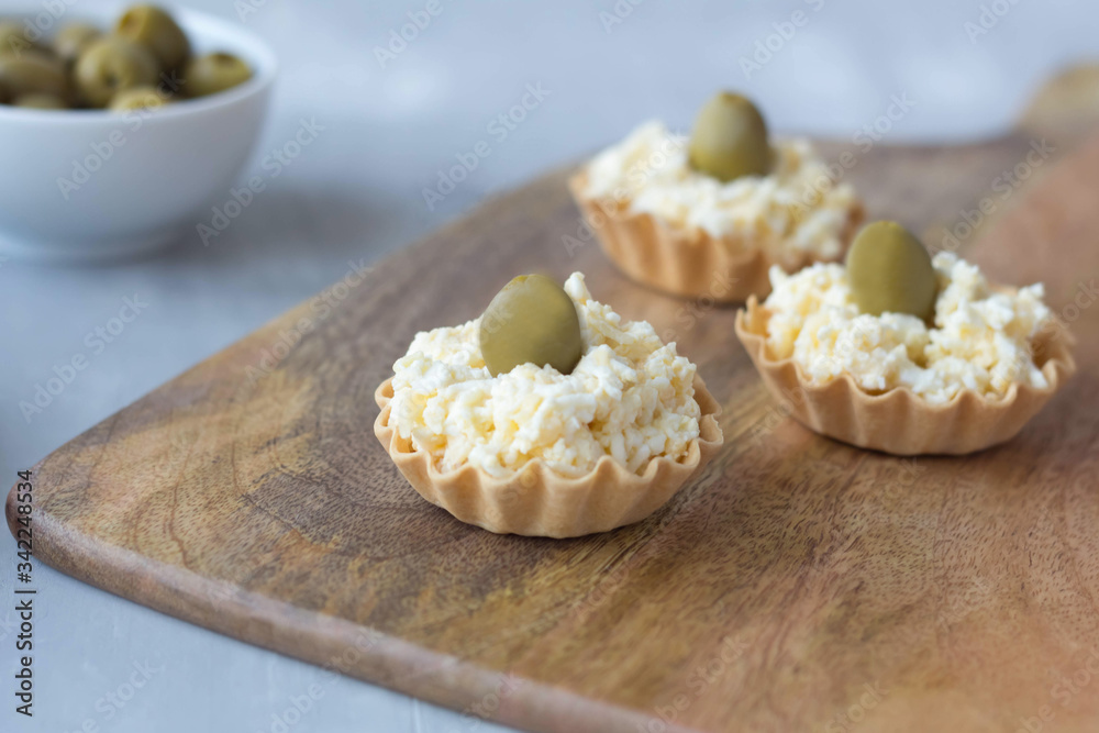 cheese snack with olives in baskets of dough on a wooden board cheese snack with olives in baskets of dough on a wooden board