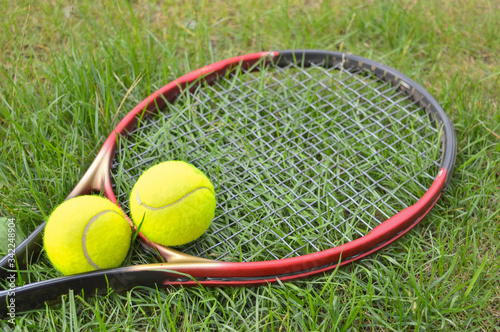 tennis racket and yellow balls lying on the grass, ready for training and games