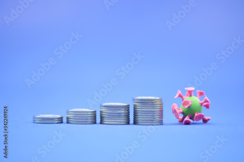 Money, Financial,Saving, Business Growth concept, Closeup of stack of coins and mini corona virus ball on blue background and copy space for text.