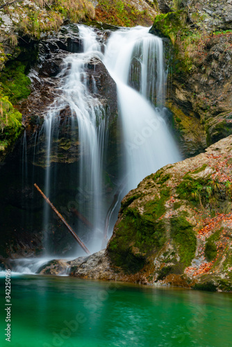 Fototapeta Naklejka Na Ścianę i Meble -  fallen tree trunk in the green lake and waterfall